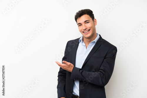 Handsome man over isolated white wall extending hands to the side for inviting to come
