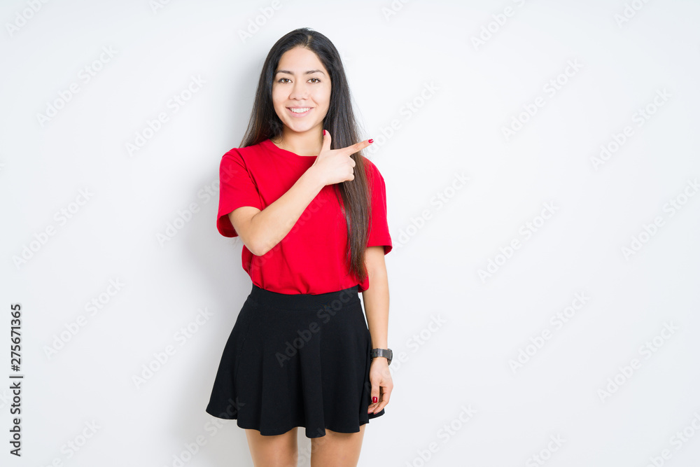 Beautiful brunette woman wearing red t-shirt and skirt over isolated background cheerful with a smile of face pointing with hand and finger up to the side with happy and natural expression on face Beautiful brunette woman wearing red t-shirt and skirt over isolated background cheerful with a smile of face pointing with hand and finger up to the side with happy and natural expression on face