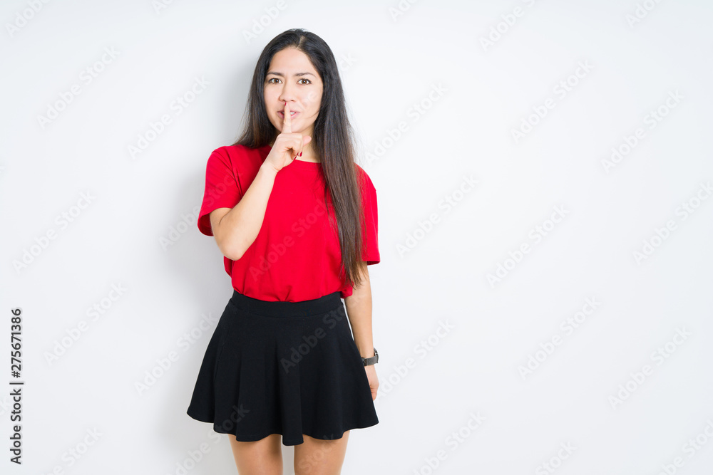 Beautiful brunette woman wearing red t-shirt and skirt over isolated background asking to be quiet with finger on lips. Silence and secret concept. Beautiful brunette woman wearing red t-shirt and skirt over isolated background asking to be quiet with finger on lips. Silence and secret concept.