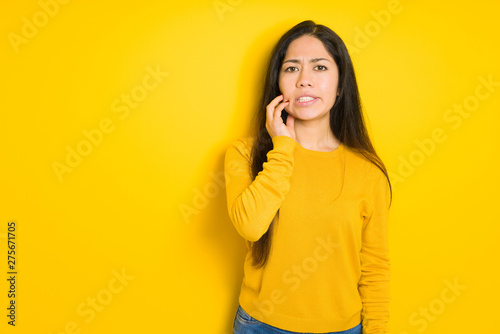 Beautiful brunette woman over yellow isolated background touching mouth with hand with painful expression because of toothache or dental illness on teeth. Dentist concept. © Krakenimages.com