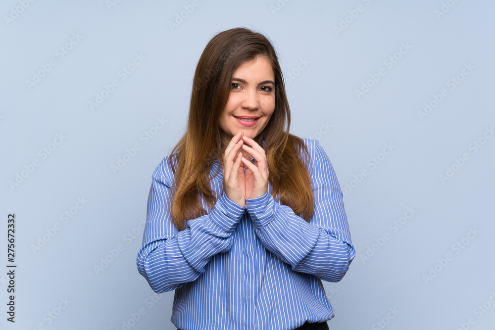 Young girl over isolated blue wall scheming something Young girl over isolated blue wall scheming something