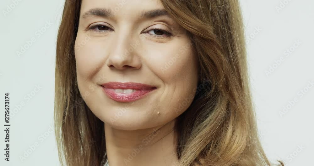 Close up of the Caucasian attractive middle aged woman standing back to the camera and then turning face and smiling to the camera. Portrait.