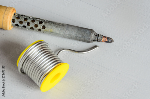 solder wire and soldering iron with wooden handle on gray background