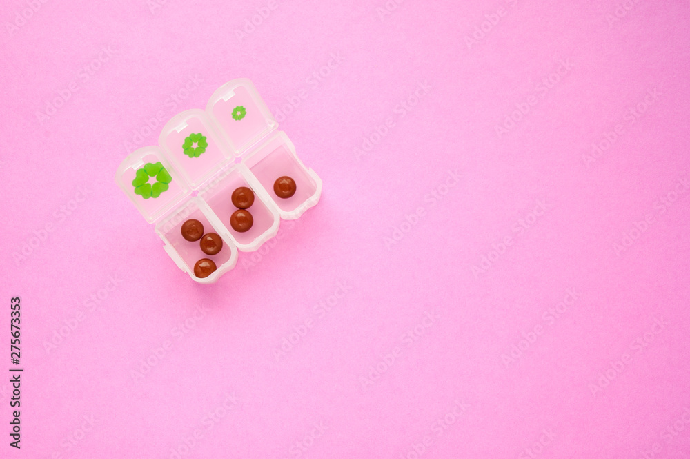 Brown tablets in pill box for three days on pink background three two one in top left. copyspace for text. Health, disease treatment concepts Brown tablets in pill box for three days on pink background three two one in top left. copyspace for text. Health, disease treatment concepts