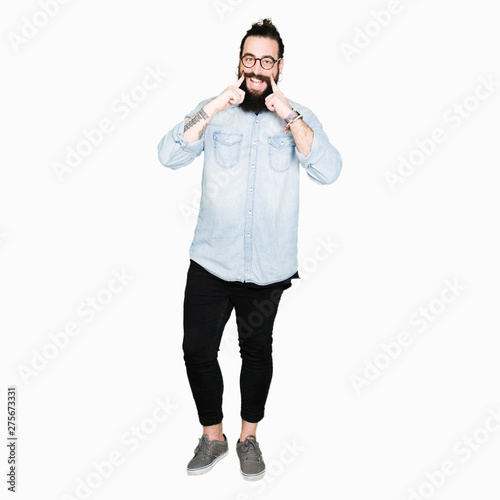 Young hipster man with long hair and beard wearing glasses Smiling with open mouth, fingers pointing and forcing cheerful smile