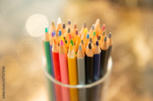 close up color pencils in box on wooden table , blurred bokeh background .