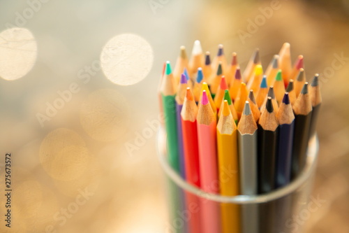 close up color pencils in box on wooden table , blurred bokeh background . copy space for text .