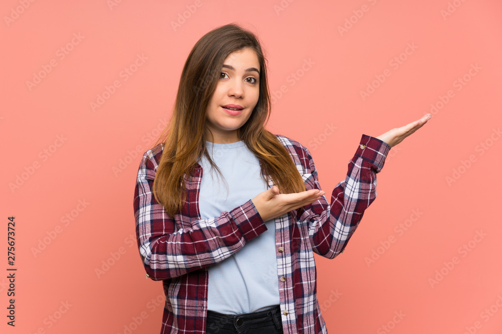 Young girl over pink wall extending hands to the side for inviting to come Young girl over pink wall extending hands to the side for inviting to come