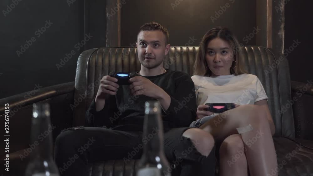 Portrait handsome young guy with his girlfrend having fun playing video games with excellent mood in modern loft club. Video game and leisure concept. Portrait handsome young guy with his girlfrend having fun playing video games with excellent mood in modern loft club. Video game and leisure concept.