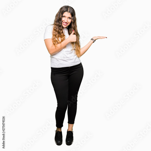 Young beautiful woman wearing casual white t-shirt Showing palm hand and doing ok gesture with thumbs up, smiling happy and cheerful