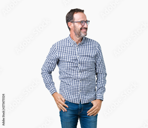 Handsome middle age elegant senior business man wearing glasses over isolated background looking away to side with smile on face, natural expression. Laughing confident.