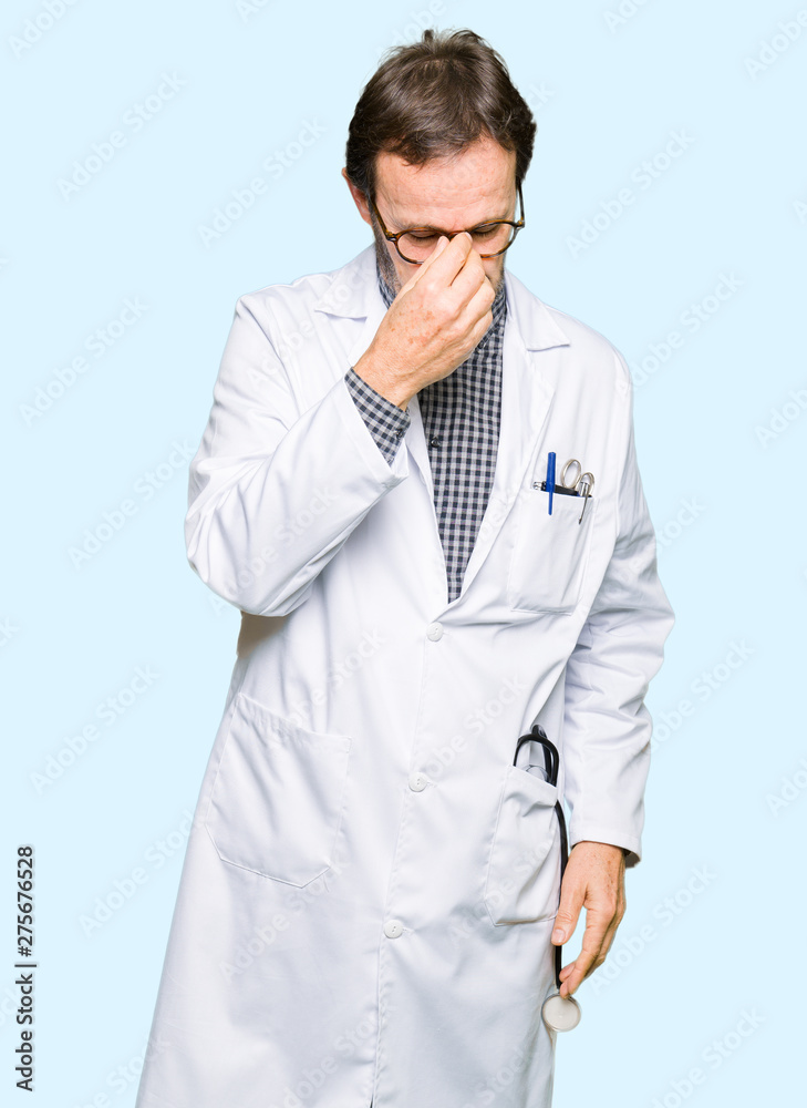 Middle age doctor men wearing medical coat tired rubbing nose and eyes feeling fatigue and headache. Stress and frustration concept. Middle age doctor men wearing medical coat tired rubbing nose and eyes feeling fatigue and headache. Stress and frustration concept.