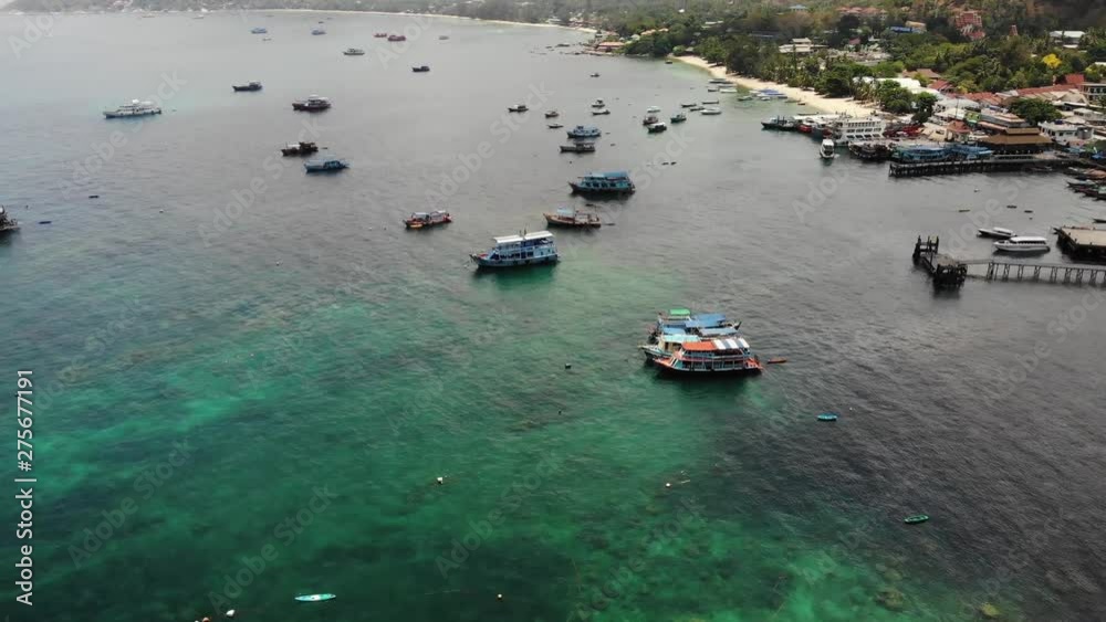 Boats in calm sea in port. Drone view of fishing and dive boats floating on tranquil surface of blue sea in harbor of tropical exotic paradise Koh Tao Island on sunny day in Thailand. Boats in calm sea in port. Drone view of fishing and dive boats floating on tranquil surface of blue sea in harbor of tropical exotic paradise Koh Tao Island on sunny day in Thailand.