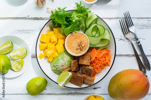 Healthy summer fresh salad with mango  avocado  lime and tofu with sweet peanut butter dressing on white wooden table