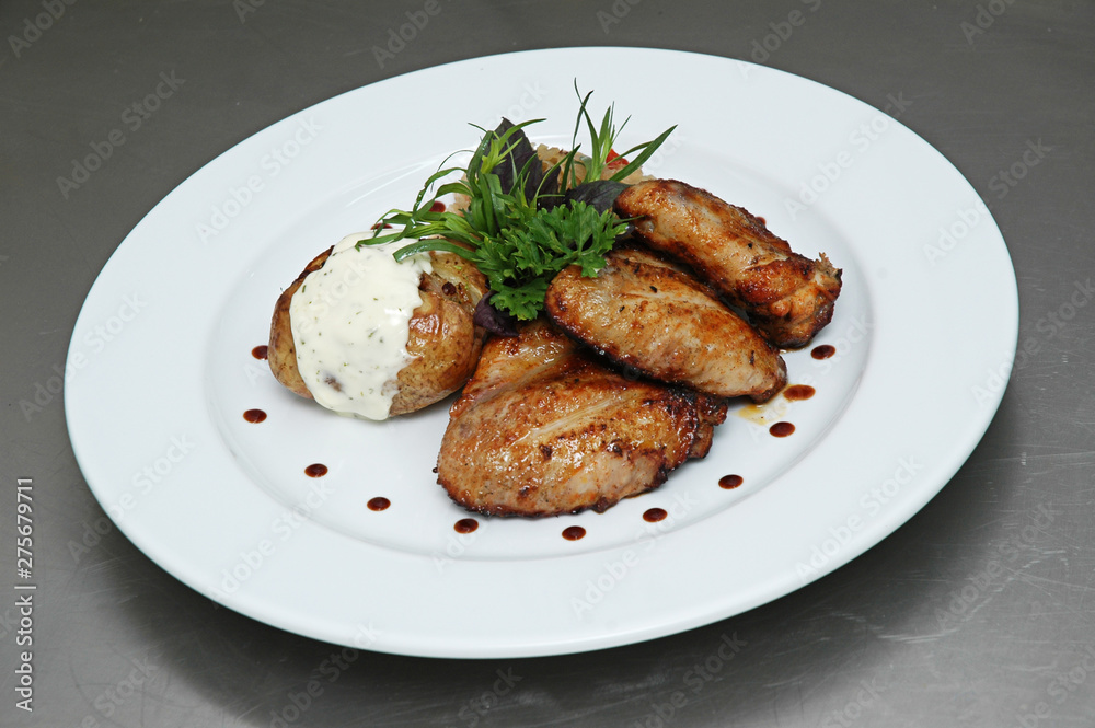 Chicken wings, stuffed potatoes, mint, dill, on a plate on a gray background