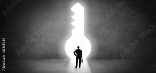 Businessman standing alone in front of a big keyhole
