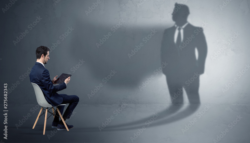 Fototapeta premium Humble businessman staying and offering stuffs to a huge angry bull shadow 