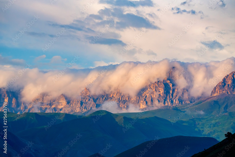 Scenic view of foggy mountains. Sunlit rocks and clouds