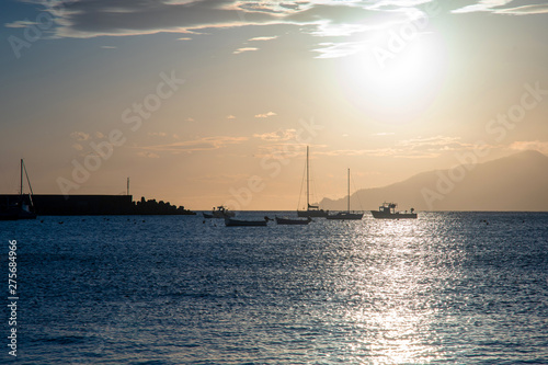 Backlight scenic view of the Bay of Fairy Tales in the fishing village of Sestri Levante with boats moored in the small harbor and the coastline in the background at sunset, Genoa, Liguria, Italy © Simona Sirio