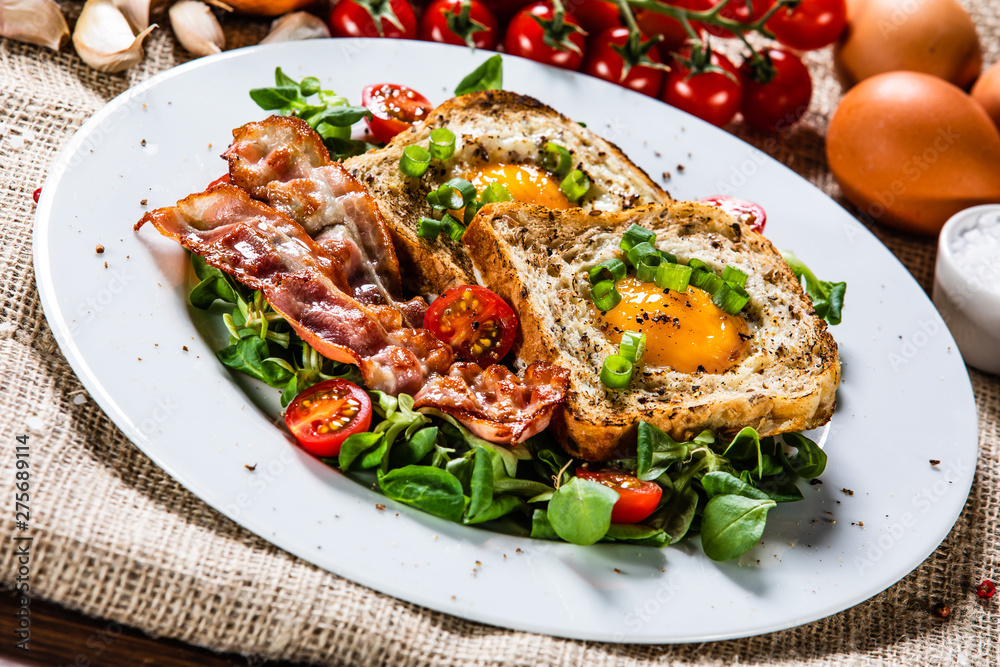 Breakfast - toasted bread with fried egg, bacon and vegetables Breakfast - toasted bread with fried egg, bacon and vegetables