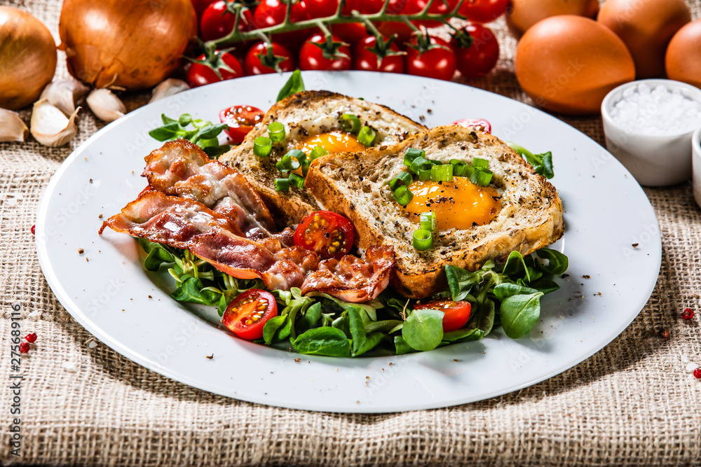 Breakfast - toasted bread with fried egg, bacon and vegetables