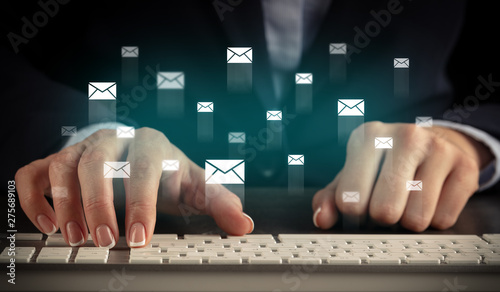Business woman typing on keyboard with mail icons around
