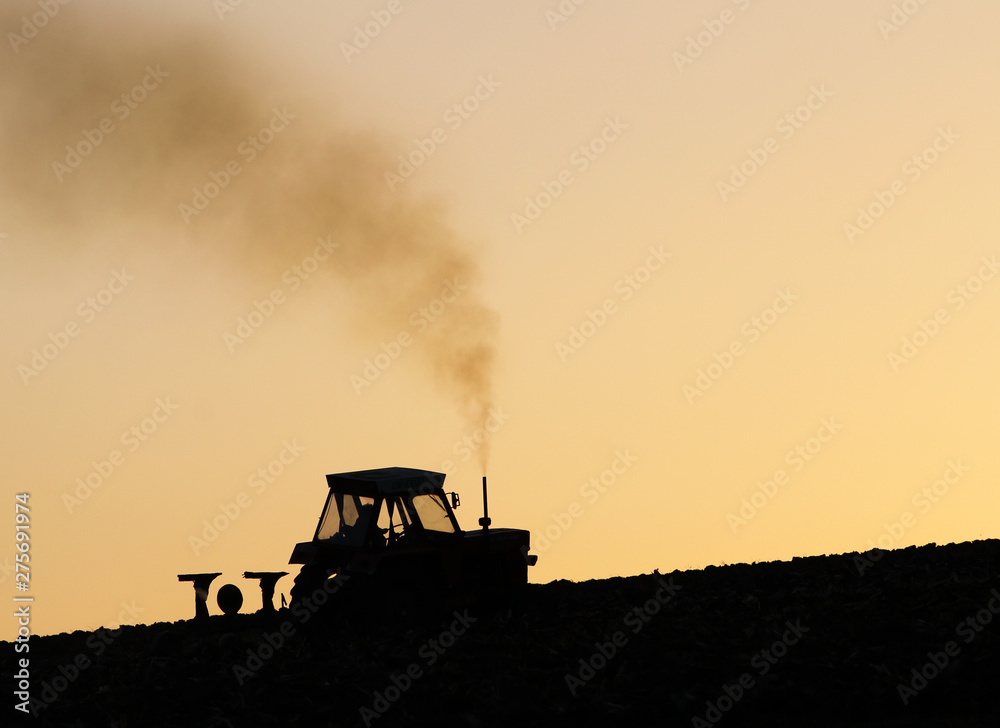 Fototapeta premium Tractor plowing the land at dawn