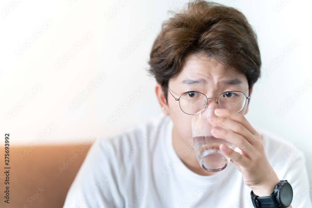 Asian Young man wearing eyeglasses and his drinking a glass of water. healthy concept - water for life. Water is my number one choice for beverage ! Asian Young man wearing eyeglasses and his drinking a glass of water. healthy concept - water for life. Water is my number one choice for beverage !