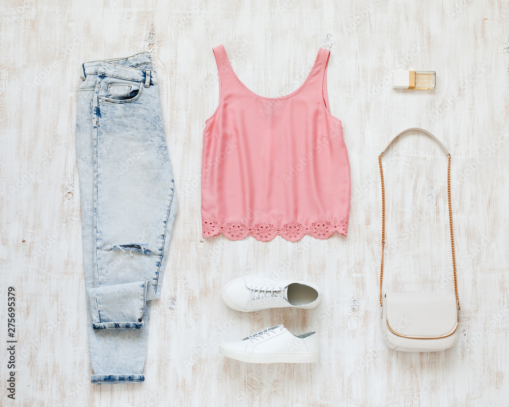 Foto Stock Pink tank top, blue denim jeans, white sneakers, small white  cross body bag with chain strap on white wooden background. Woman's casual  day outfit. Trendy spring summer look in pastel
