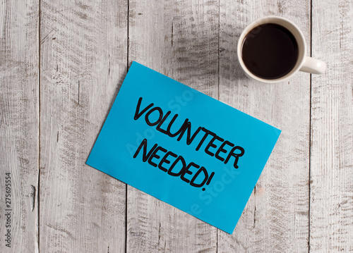 Text sign showing Volunteer Needed. Business photo showcasing asking demonstrating to work for organization without being paid Pastel Colour paper placed next to a cup of coffee above the wooden table