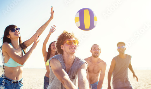 Foto Group of friends playing at beach volley at the beach