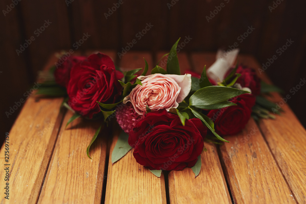 The bride holding in hand close-up the groom's buttonhole flowers with white roses, and green and greenery. Bride's Preparations. Wedding concept. The bride holding in hand close-up the groom's buttonhole flowers with white roses, and green and greenery. Bride's Preparations. Wedding concept.