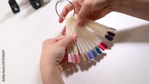 The hands of the girl choose a sample of nail polish for manicure.