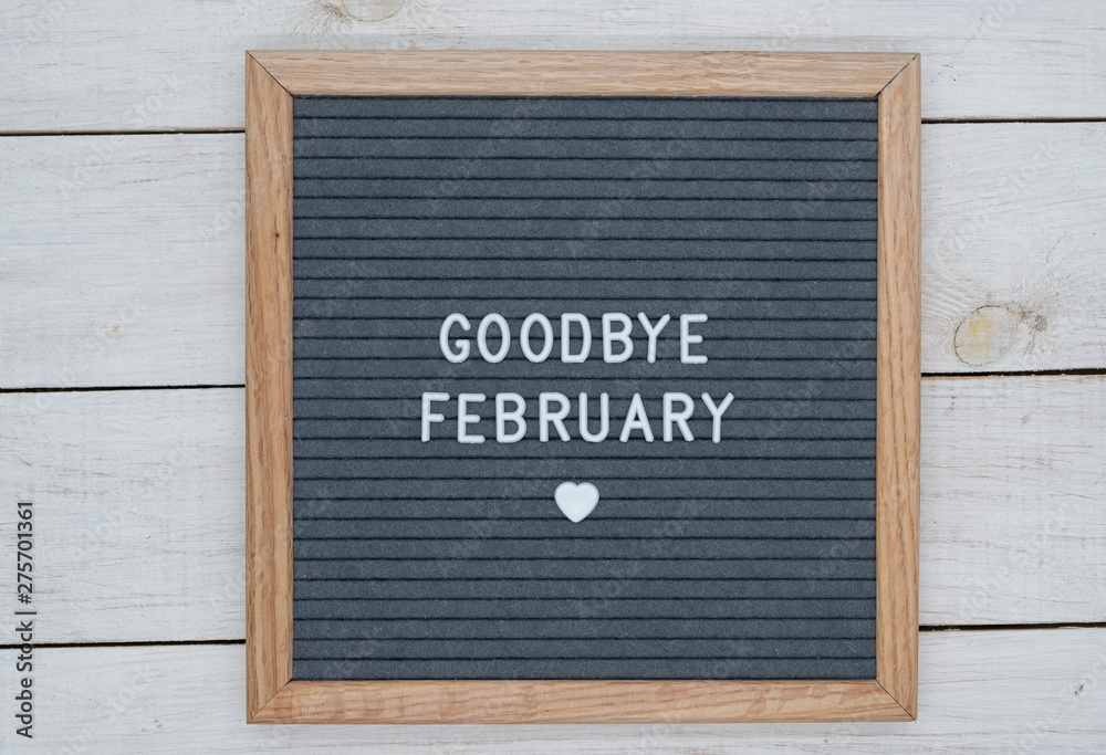 text in English goodbye February and a heart sign on a gray felt Board in a wooden frame