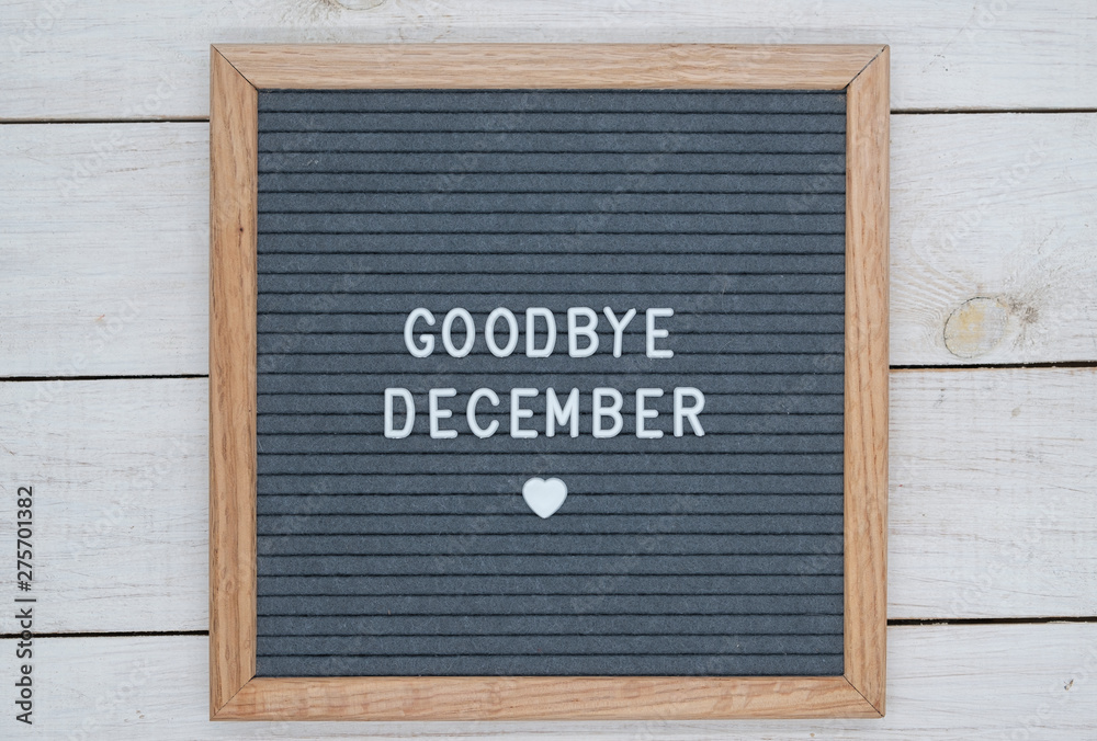 text in English goodbye December and a heart sign on a gray felt Board in a wooden frame