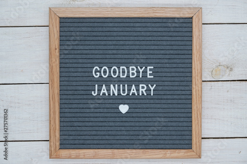 text in English goodbye January and a heart sign on a gray felt Board in a wooden frame