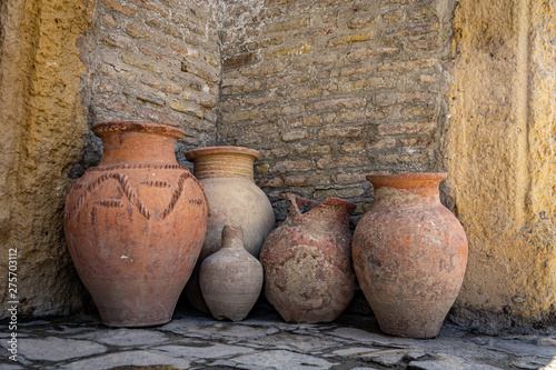 Ancient clay jars against a brick wall