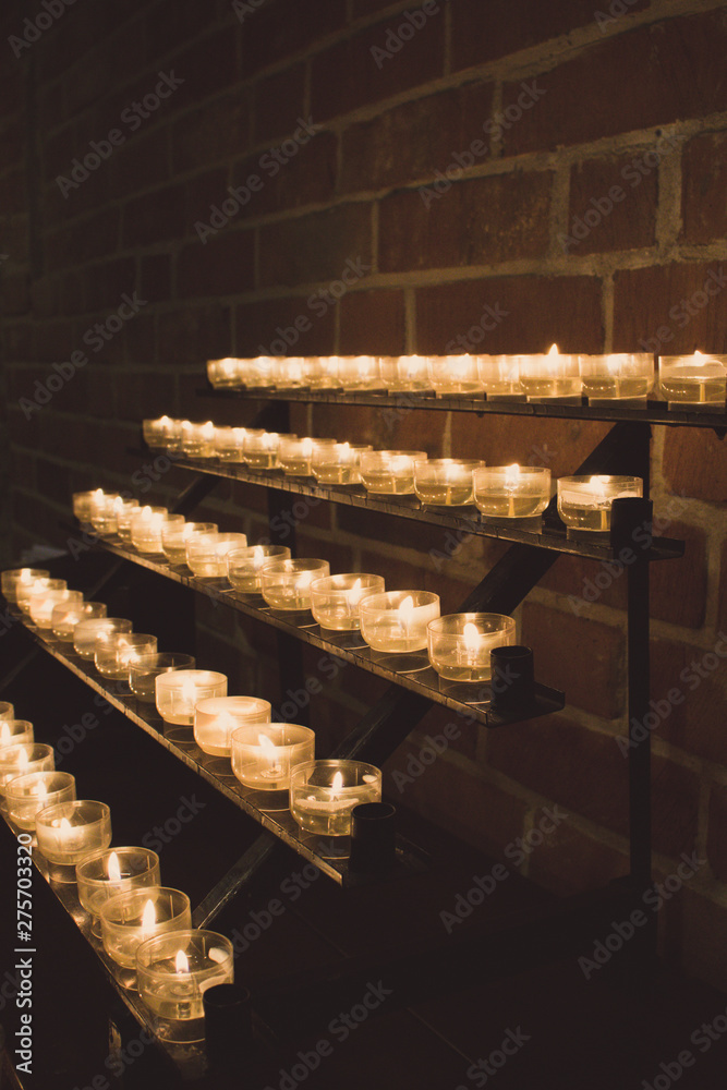 Row of glowing candles in church. Candles with flame on dark background. Faith and religion concept. Candles in catholic church. Peace and hope concept. Candlelight background. Church interior. Row of glowing candles in church. Candles with flame on dark background. Faith and religion concept. Candles in catholic church. Peace and hope concept. Candlelight background. Church interior.