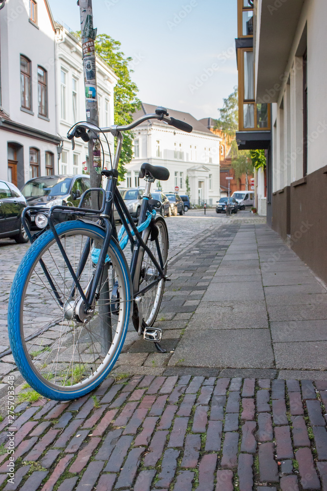 Classic bicycle with blue wheels on city street. Urban transport concept. Parking bike in town. Antique bike on street. Travel and tourism concept. Urban style. Classic bicycle with blue wheels on city street. Urban transport concept. Parking bike in town. Antique bike on street. Travel and tourism concept. Urban style.
