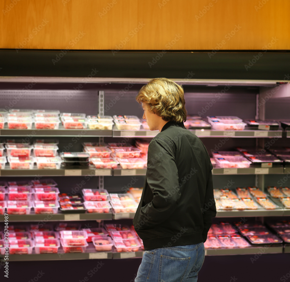 Teenager purchasing a packet of meat at the supermarket