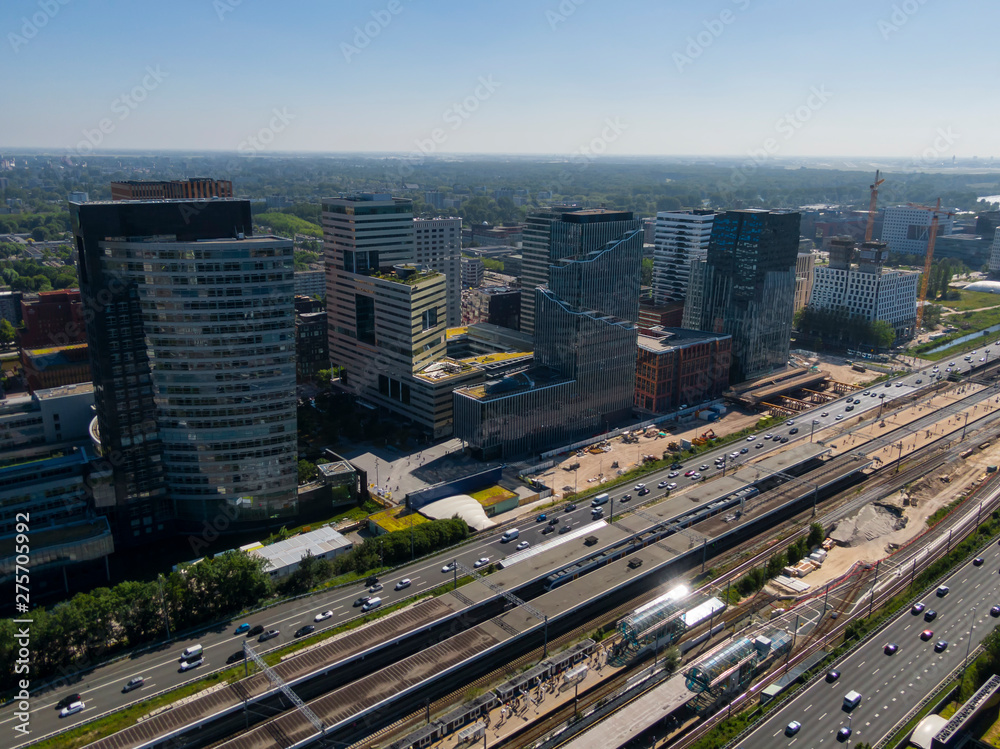 Fototapeta premium Aerial of modern office buildings on the Amsterdam Zuidas business district connected by highway and train station