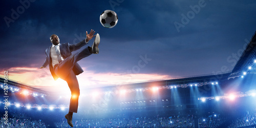 Black businessman in a suit playing footbal photo