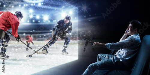 Photography Young man watching ice hockey game on TV