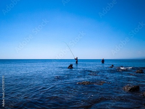 Tropical Rocky Fishing Beach Panorama With Two Fishermen Fishing On A Sunny Day At The Village, Umeanyar, North Bali, Indonesia © agratitudesign