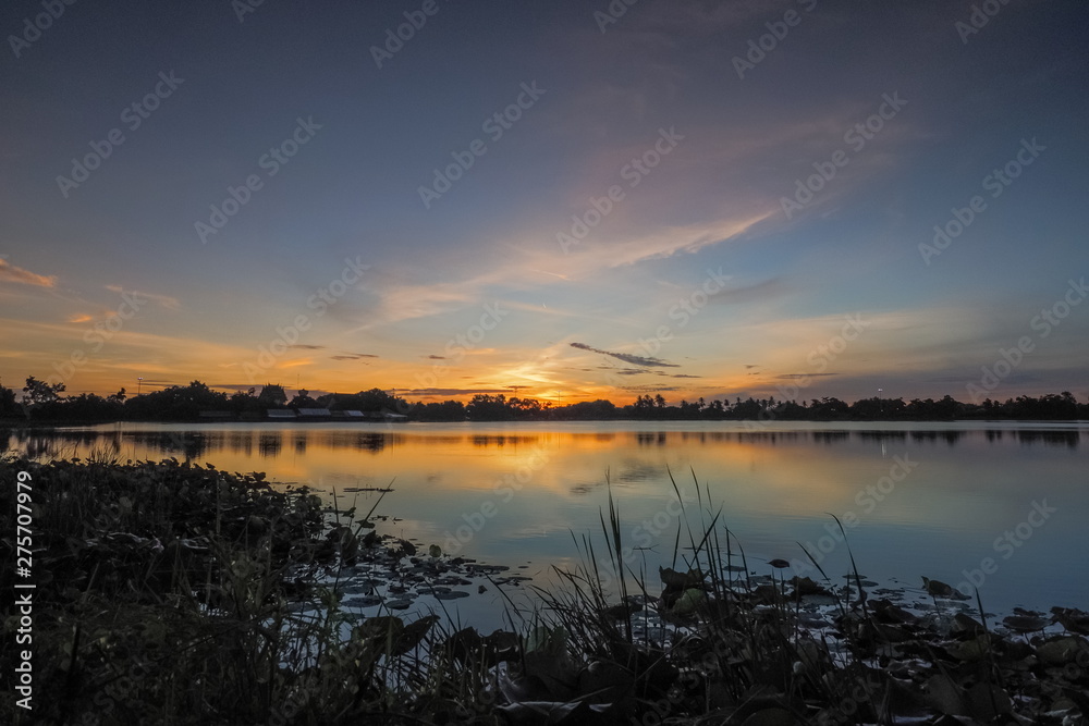 Fototapeta premium Lake view morning of yellow sun light with cloudy sky, sunrise at Krajub reservoir, Ban Pong District, Ratchaburi, Thailand.