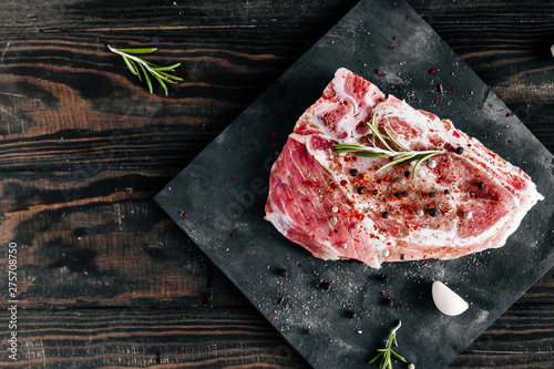 Raw piece of pork meat with rosemary and garlic dark style photo