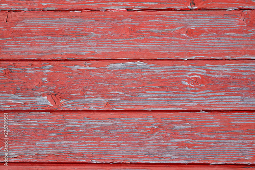 Abstract Rustic aged closeup of barn wood panel painted with red chipped and faded color. Multiple horizontal slats with wood lines with major knot and texture