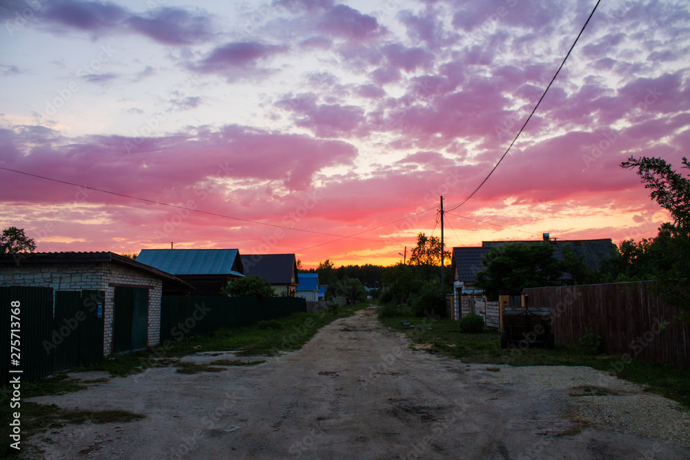 Bright purple sunset on the old village street in Russia