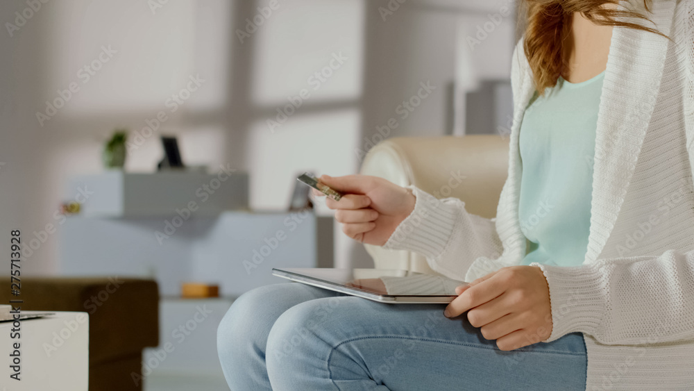 Girl paying online with bank card, using app on tablet for financial transaction Girl paying online with bank card, using app on tablet for financial transaction