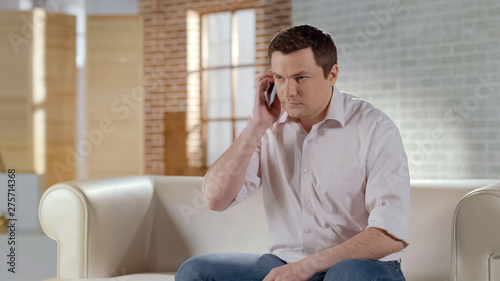 Young handsome businessman having serious phone conversation with partner
